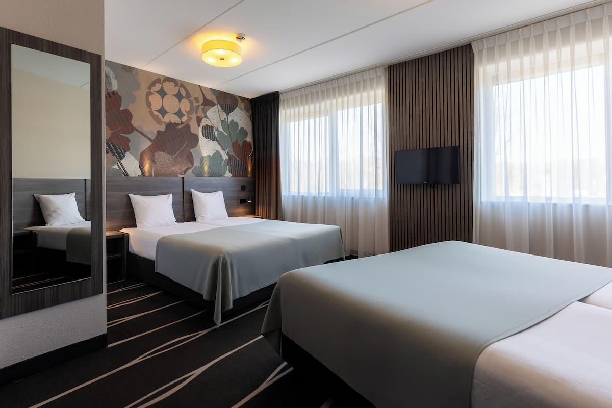 Une chambre d’hôtel avec deux lits, un grand miroir, un téléviseur à écran plat et une fresque murale décorative.
