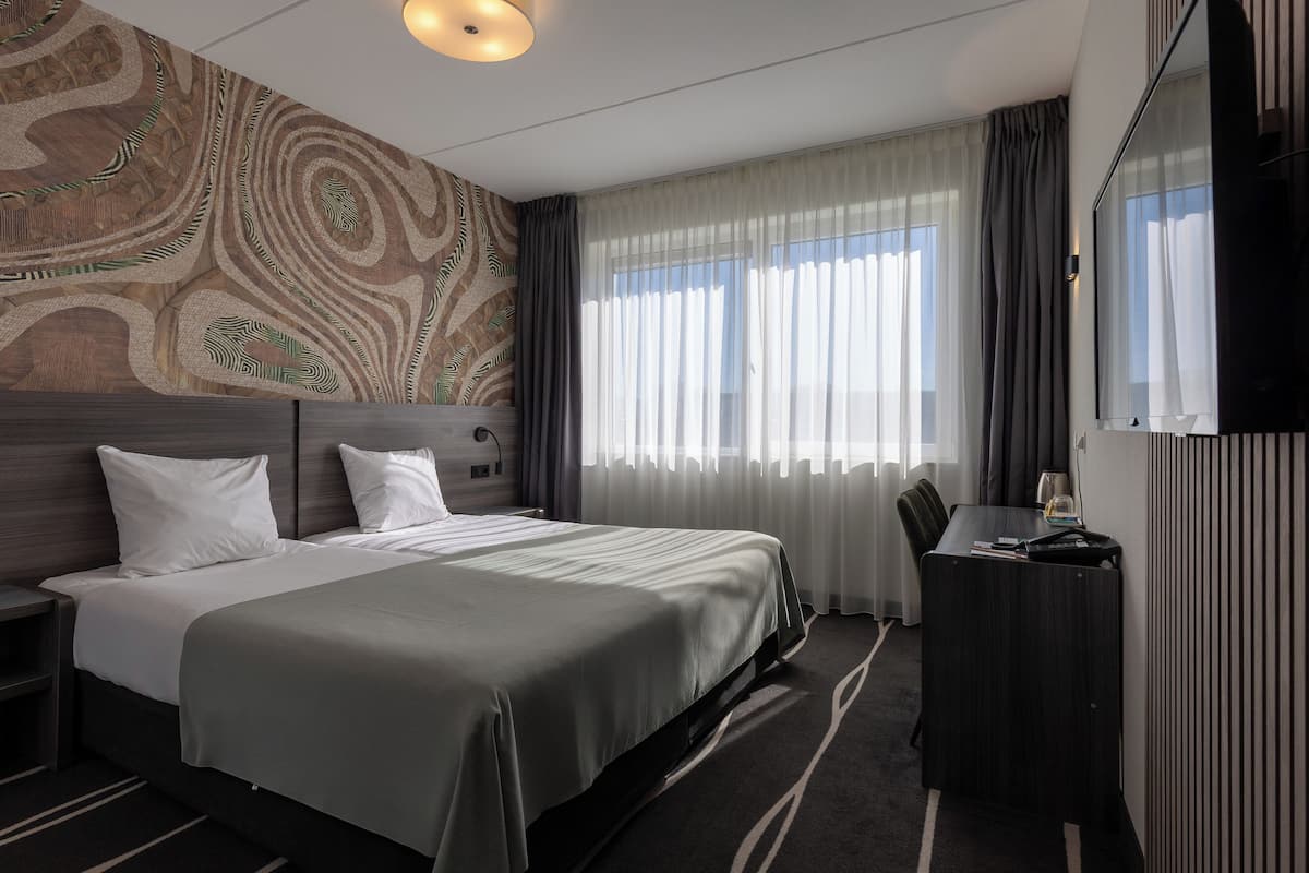 Une chambre d’hôtel avec un grand lit, un bureau et une télévision.