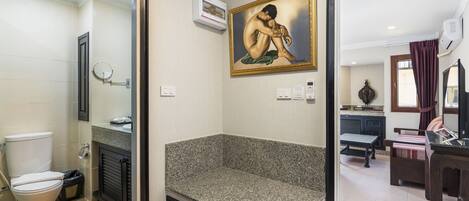 Un baño con inodoro, lavamanos y un cuadro de una figura desnuda.