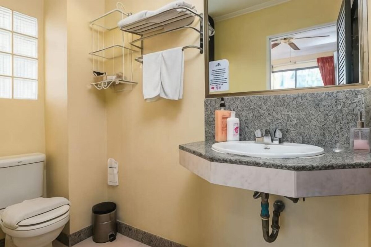 A bathroom with a toilet, sink, towel rack, and mirror.