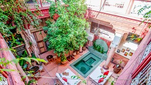 Vue aérienne d’une cour intérieure avec une piscine centrale, entourée de plantes en pot et d’un espace salon extérieur.