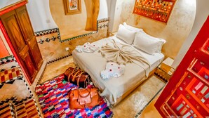 Une chambre à coucher avec un lit, des oreillers, une couverture, une couette et un tapis.