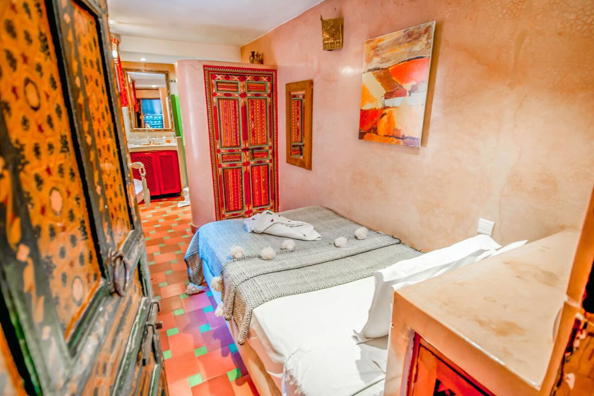 Een kamer met een bed, een dressoir, een spiegel en een deur met ingewikkelde versieringen.