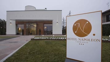 Una entrada de hotel moderna con un letrero que muestra el logotipo y el nombre "HOTEL NAPOLEON CHERASCO".