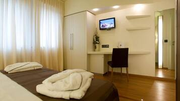 Une chambre d’hôtel comprenant un lit, un bureau avec une chaise, une télévision et une porte.