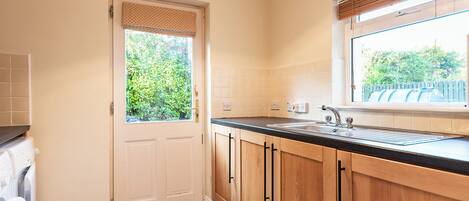 A kitchen with wooden cabinets, a sink, and a window with blinds.