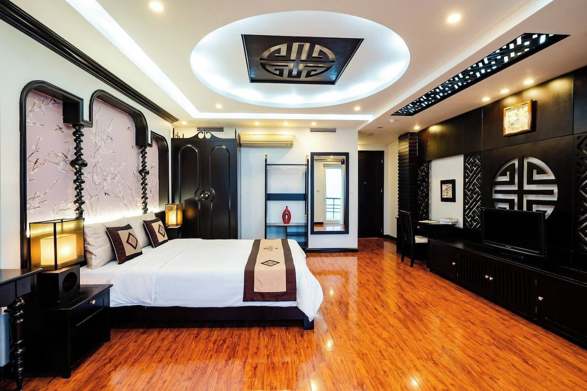 A modern hotel room with a large bed, a desk, and a wardrobe.