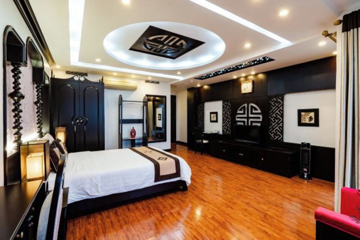 A modern hotel room with a large bed, a desk, and a seating area.
