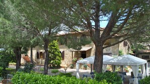 Un bâtiment en pierre, à l’aspect rustique, entouré d’une végétation luxuriante et doté d’espaces de détente en plein air.