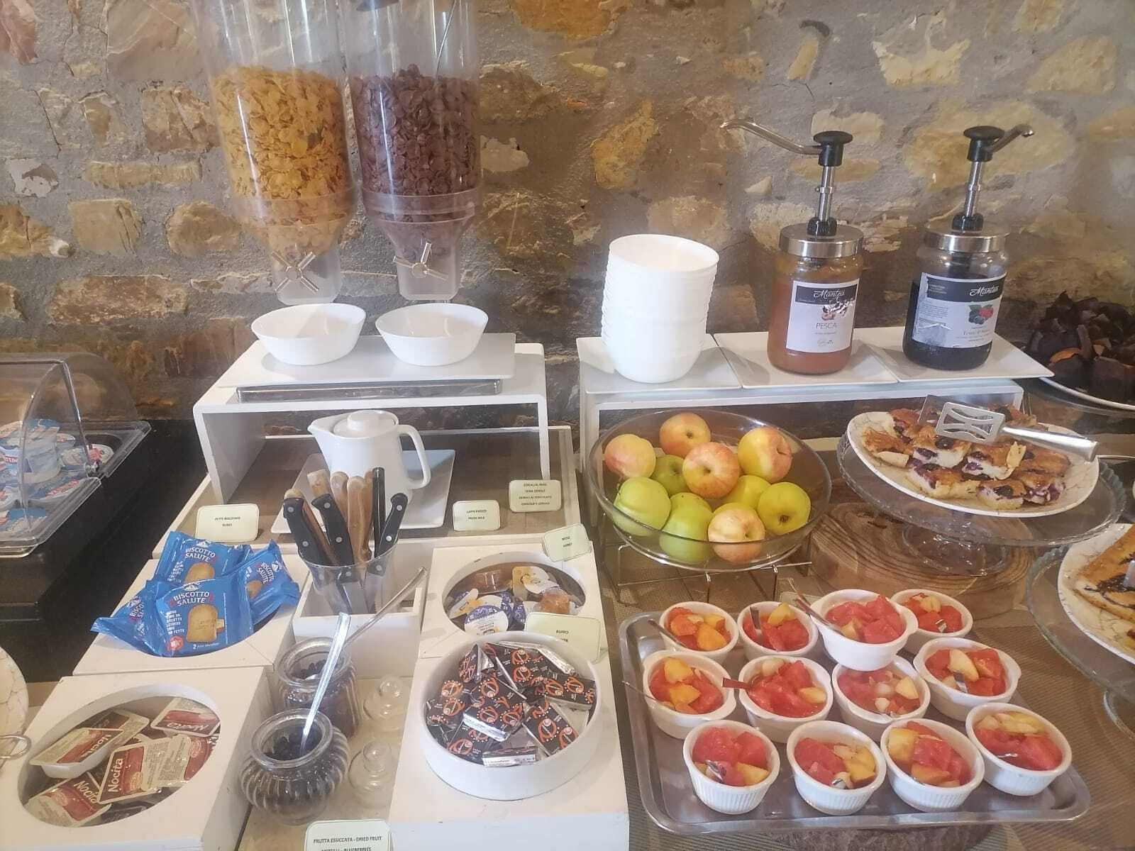 Un buffet proposant une variété de plats, notamment des fruits, des pâtisseries et des condiments.