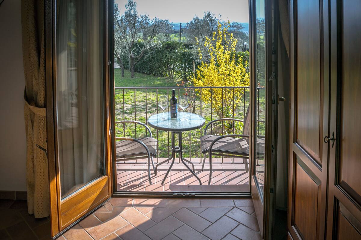 A balcony with a glass door, a round table, and two chairs.