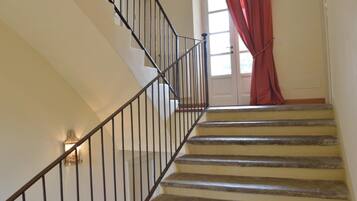 A staircase with a handrail and a light fixture on the wall.