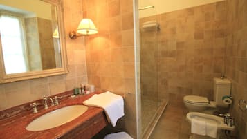 A bathroom with a marble sink, a glass shower enclosure, and a toilet.