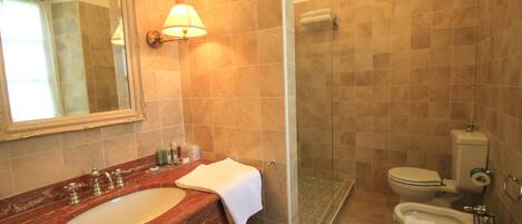 A bathroom with a marble sink, a glass shower enclosure, and a toilet.