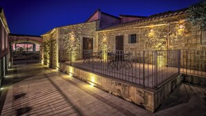 A stone building with a balcony, metal railing, and outdoor seating.