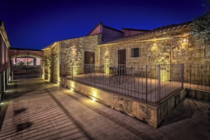A stone building with a balcony, metal railing, and outdoor seating.
