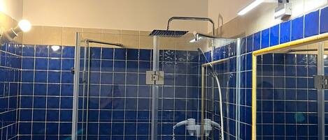 A bathroom with a glass-enclosed shower, a sink with a mirror, and blue-tiled walls.