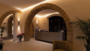 A lobby with arched brick ceilings, a reception desk, and potted plants.