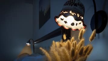 A room with a bed, a wall-mounted lamp, and a decorative wall piece.