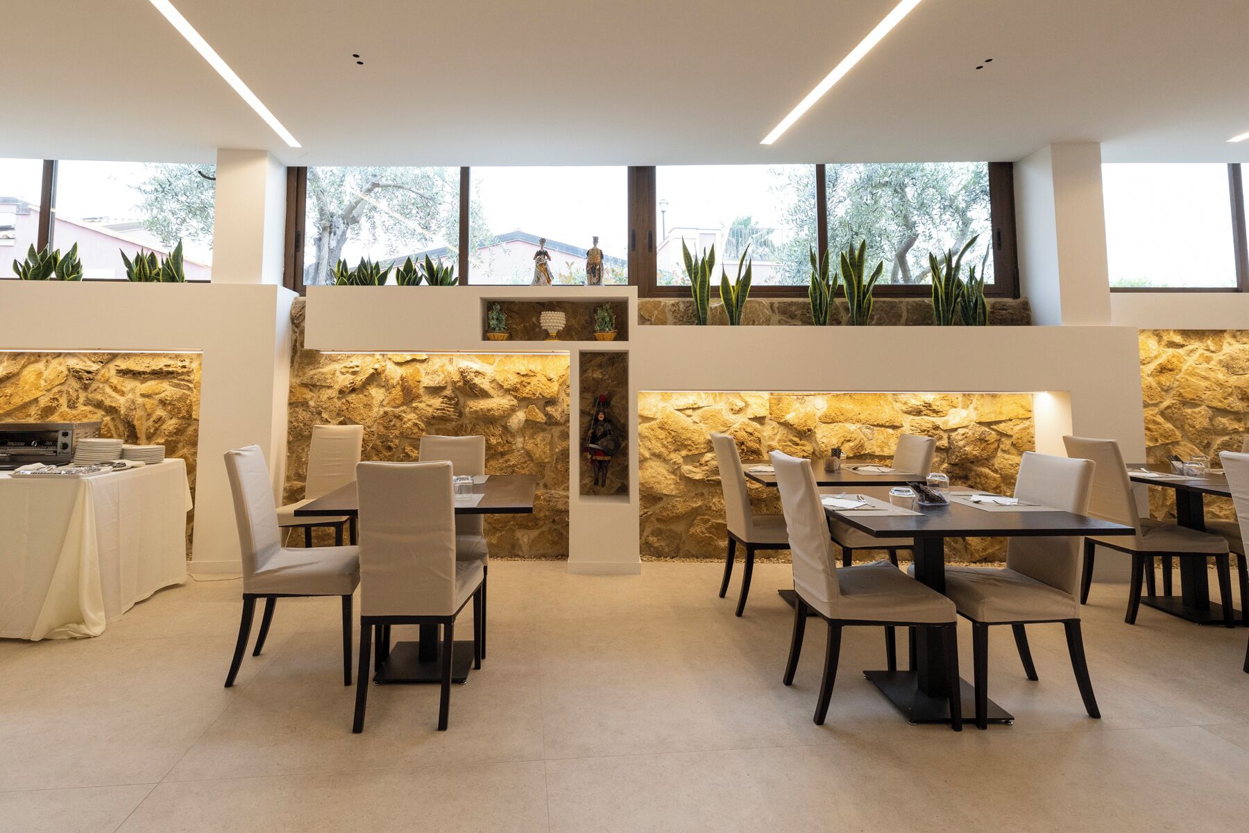 A modern restaurant with stone walls, multiple tables, and chairs.