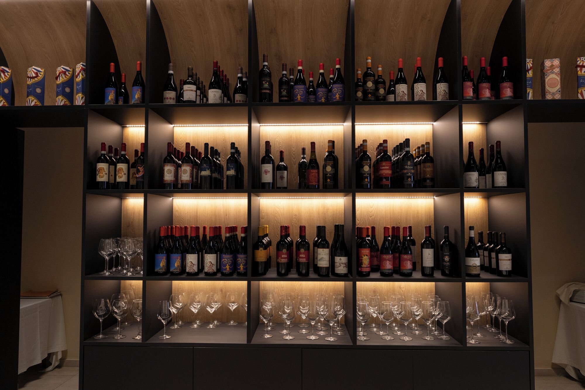 A wine cellar with multiple shelves of wine bottles and glasses.