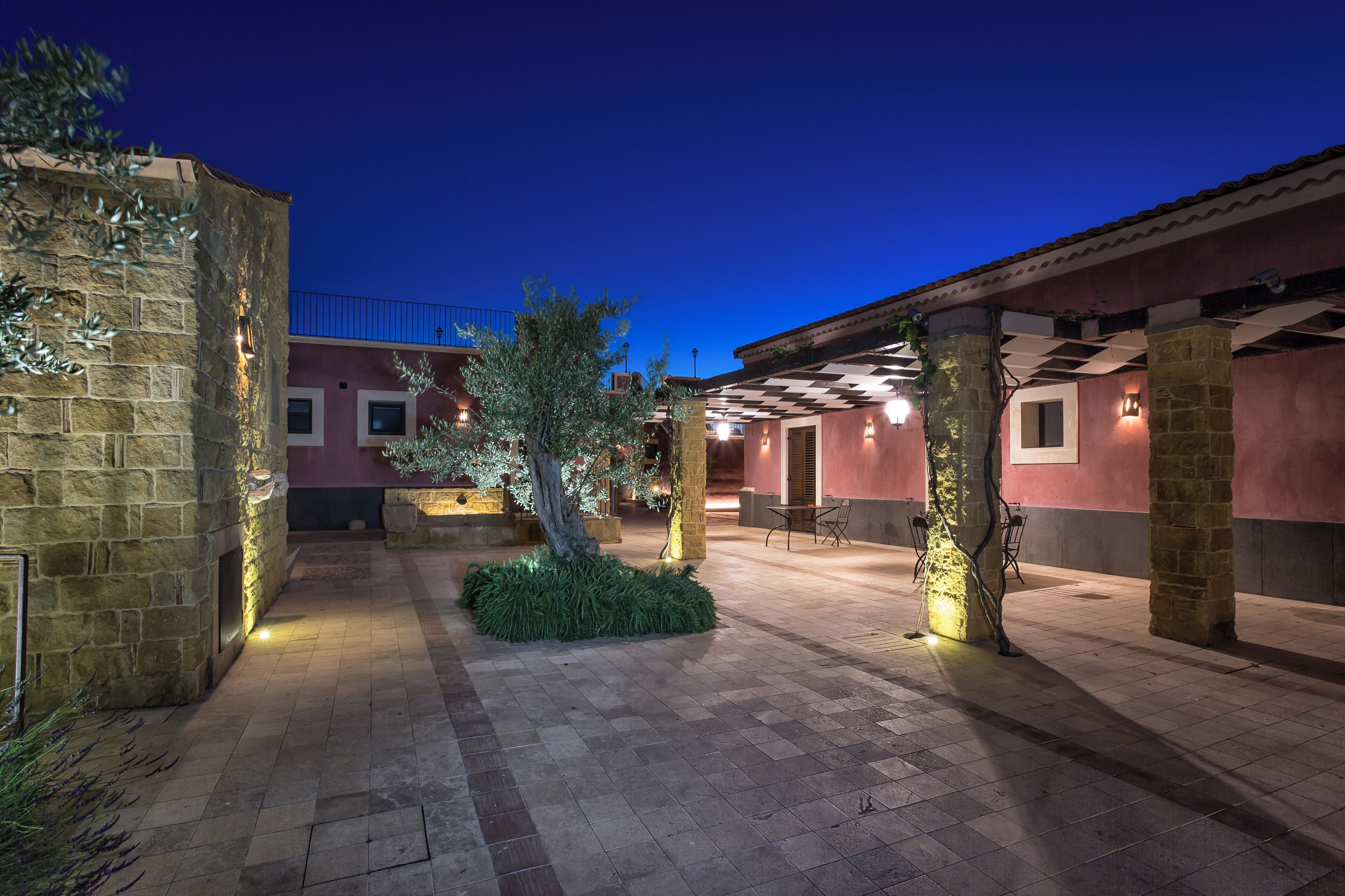 An outdoor courtyard with stone walls, a tree, and a checkered ceiling.