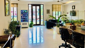 A modern living room with a sofa, a desk with a computer, and a Grubox vending machine. - Hotel City Premier (Gurugram)