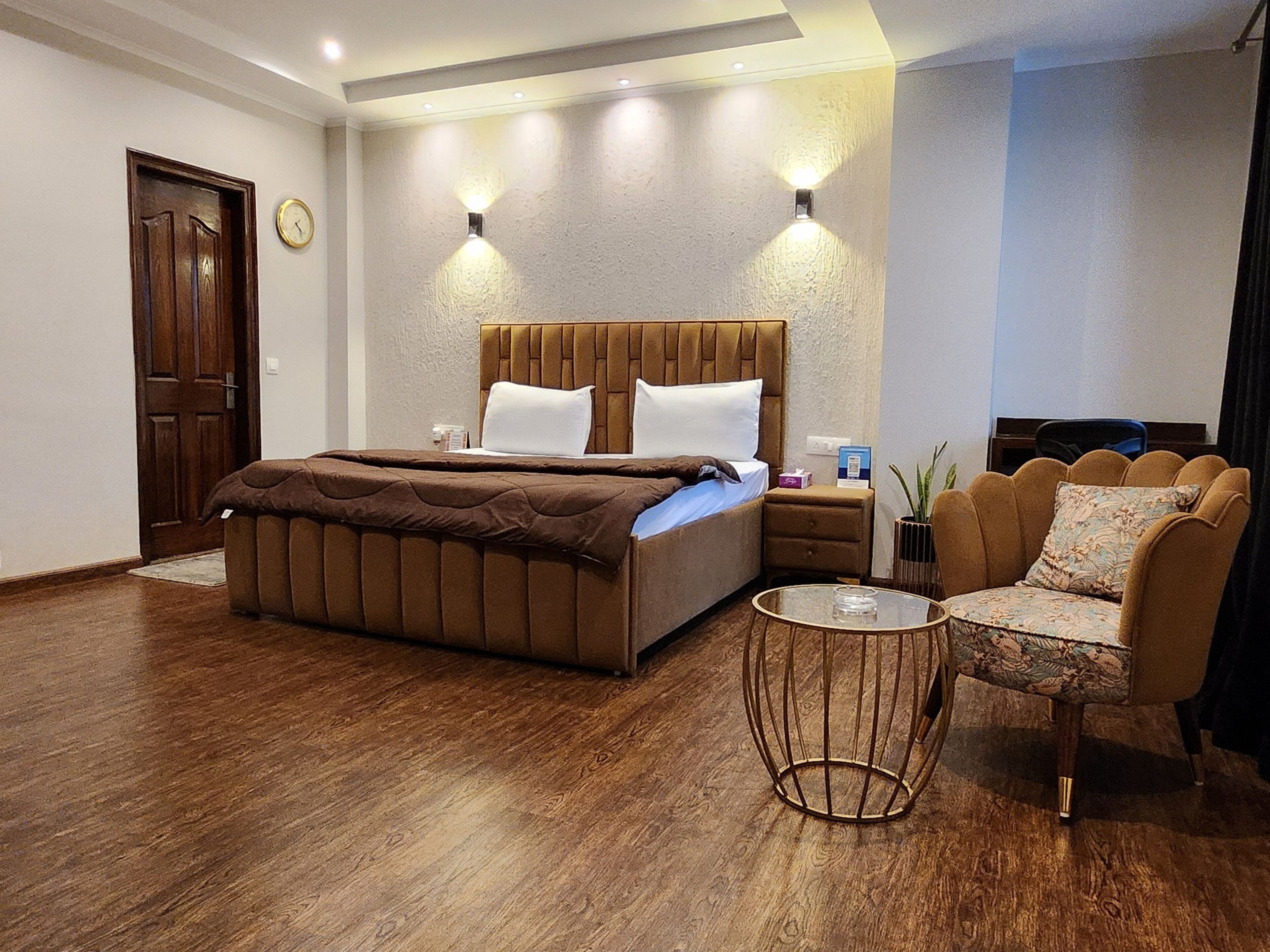 A hotel room with a bed, a nightstand, a chair, and a small table.