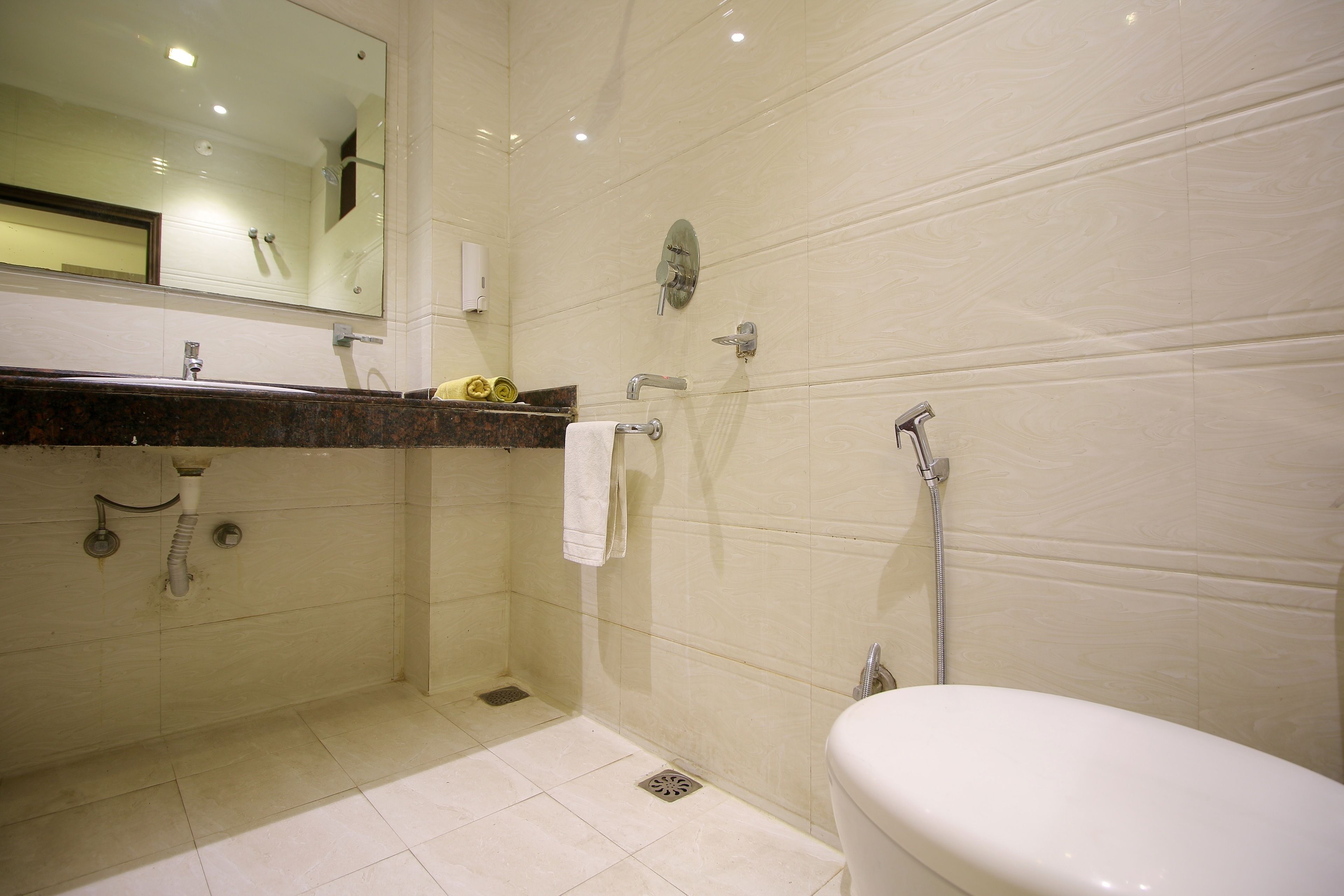 A bathroom with a white toilet, a sink with a mirror above it, and a shower area.