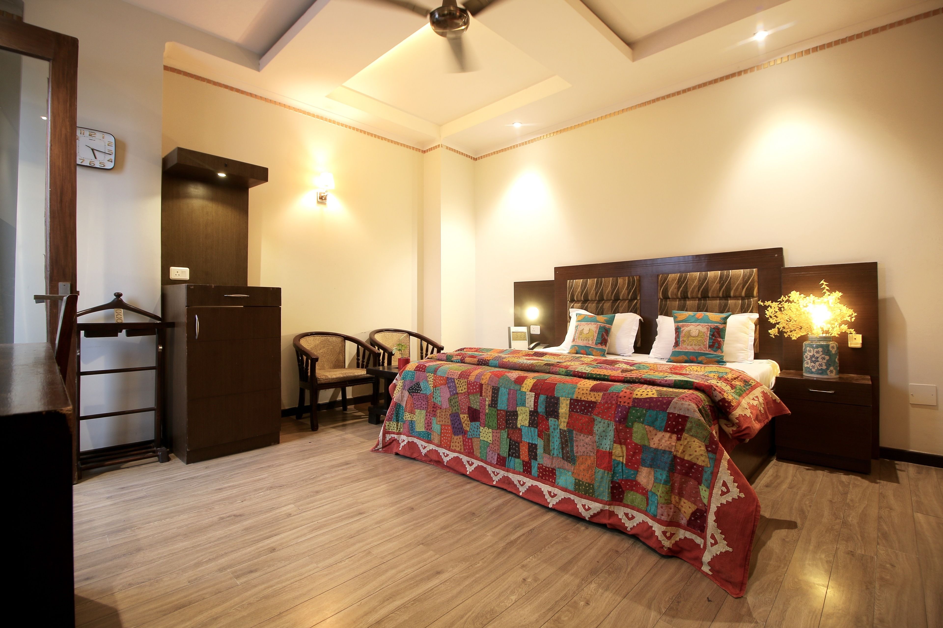 A bedroom with a large bed, a wooden wardrobe, a desk, and a chair.