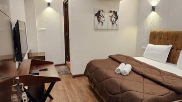 A hotel room with a bed, a desk, a TV, and an air conditioner.
