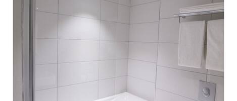 A modern bathroom with a glass-enclosed shower, a white bathtub, and a toilet.