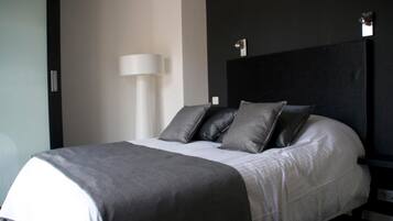 A modern hotel room with a neatly made bed, a bedside lamp, and a dark headboard.