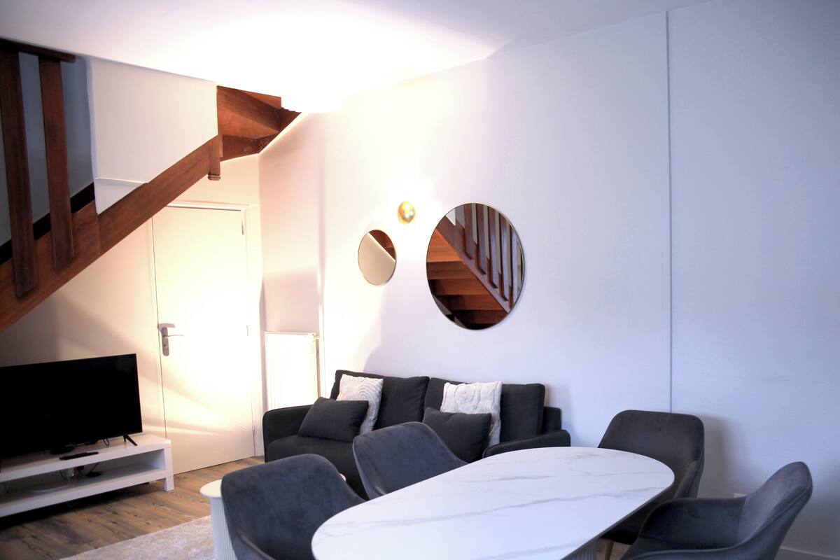 Un salon moderne avec un ensemble de canapés, une table basse et un téléviseur posé sur un meuble.
