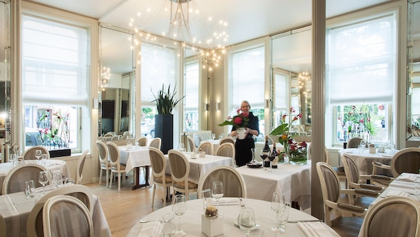 A restaurant with round tables, chairs, and a chandelier. - Les Capucins (Belfort)