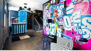 A modern interior with a staircase, a bar area, and a vibrant graffiti wall. - Les Capucins (Belfort)