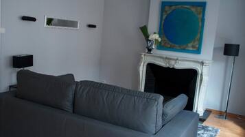 A modern living room with a grey sofa, a fireplace, and a large abstract painting.