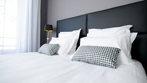 A modern hotel room with a large bed, two pillows, a bedside table, and a lamp. - Les Capucins (Belfort)