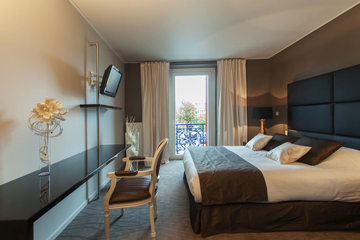 Une chambre d’hôtel équipée d’un lit, d’un bureau, d’une chaise, d’une télévision et offrant une vue sur l’extérieur.