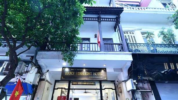 Entrada de hotel con una escalera que conduce a la puerta, un letrero y una bandera.