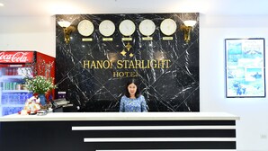 Mostrador de recepción en el Hanoi Starlight Hotel, con un fondo de mármol negro que muestra relojes y nombres de ciudades.