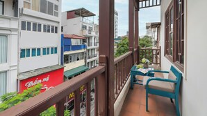 Un balcón con vistas a edificios vecinos, una mesa con sillas y un letrero rojo con texto blanco.