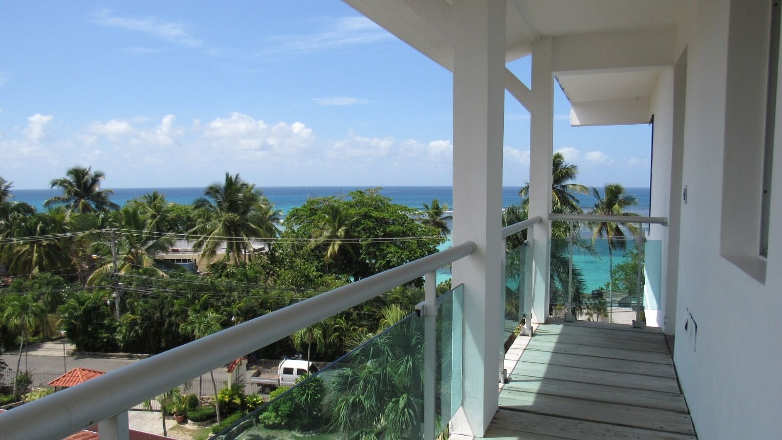 Een balkon met uitzicht op de oceaan en palmbomen.