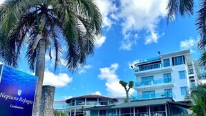 A modern building with multiple balconies and a sign for 'Neptuno Refugio Condominium'. - Hotel Refugio Neptuno's (Boca Chica)