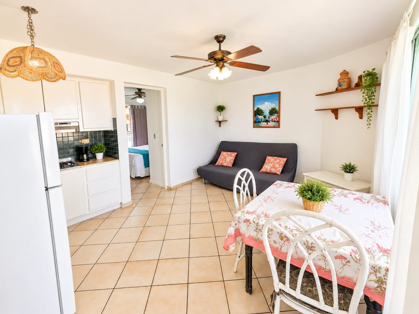 A compact living space with a kitchenette, a dining area, a sofa, and a ceiling fan.