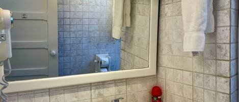 Un baño con un lavamanos blanco, un espejo, un perchero para toallas y un dispensador de papel higiénico.