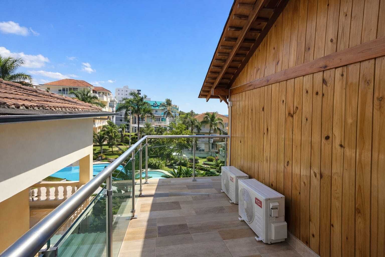 Varanda com vista para a piscina, paredes de madeira e aparelhos de ar condicionado.