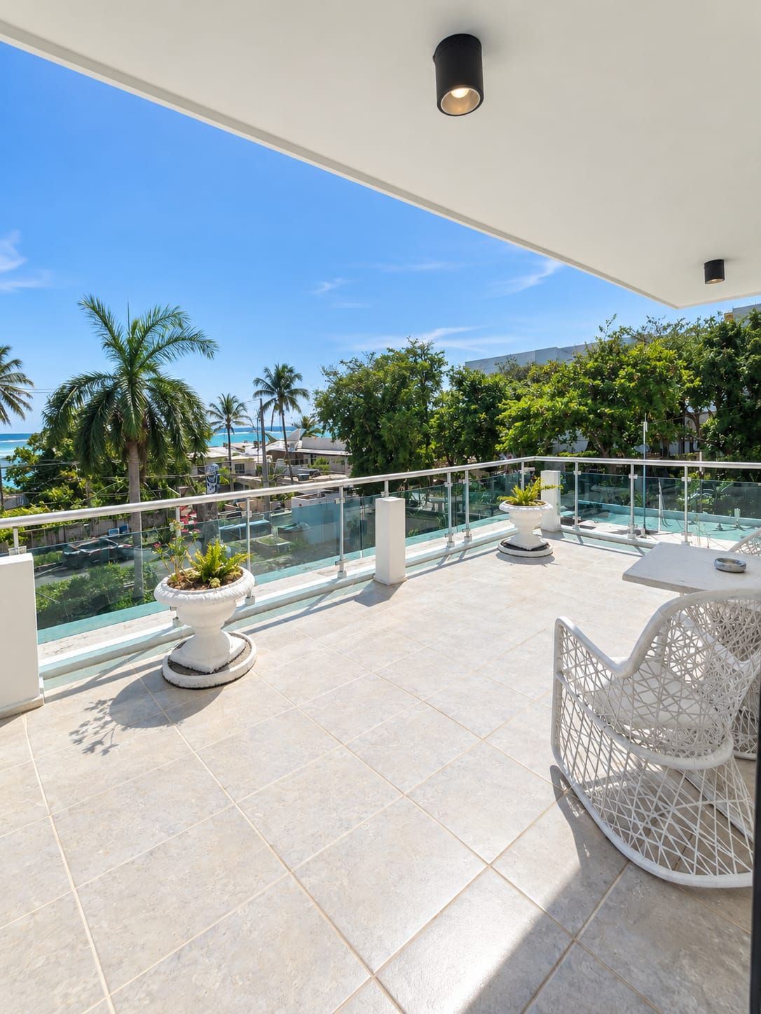 Une terrasse sur le toit dotée d’une balustrade en verre, d’un espace salon extérieur et offrant une vue sur l’océan.