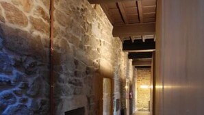 A narrow hallway with stone walls and wooden flooring, leading to a lit area at the end. - Casa Grande de Cristosende (A Teixeira)