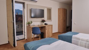 Une chambre d’hôtel comprenant un lit, un bureau avec une chaise, une télévision et une armoire.